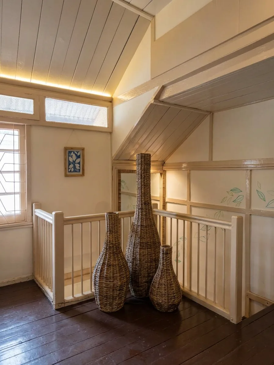 Stairwell landing decorated with tall woven cane vases beneath a framed cyanotype print